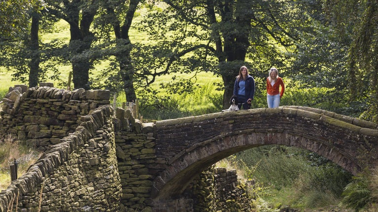 Visitors with their dog standing on Easter Gate Bridge, Marsden, Yorkshire.